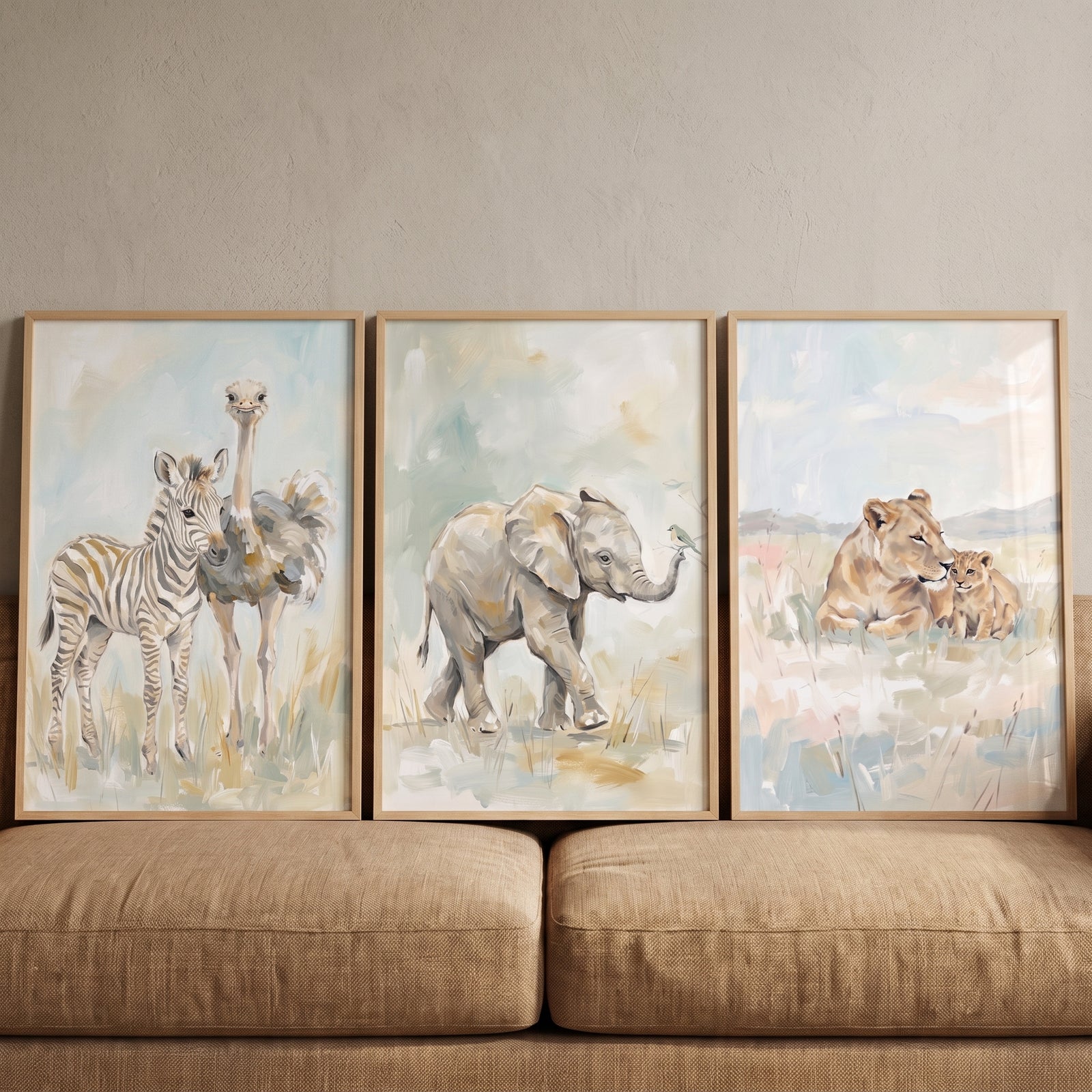 Soft neutral safari animals wall art set of 3 with a zebra, ostrich, elephant, and lions resting on a tan couch.