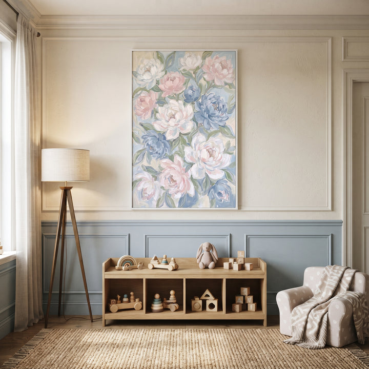 Soft painterly pink peony floral wall art hangs in a nursery with a wooden toy shelf, tripod lamp, and armchair.