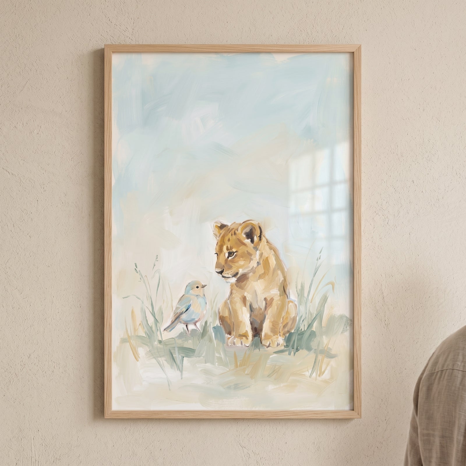Soft pastel cub lion wall art featuring a lion cub and a small blue bird in a grassy field, framed in light wood.
