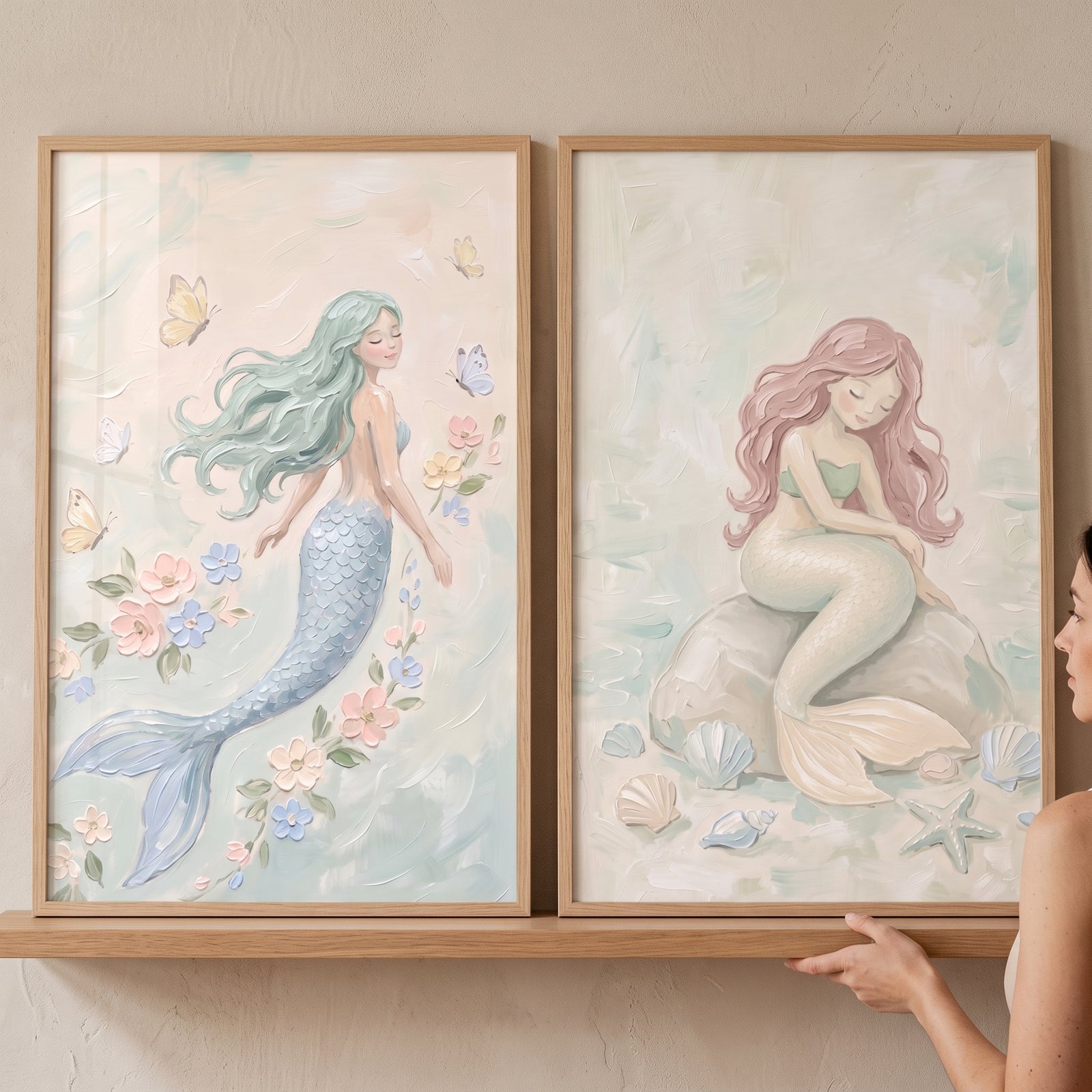 Soft pastel dreamy mermaid wall art set of 2 in wood frames, featuring one mermaid swimming and another on a rock.