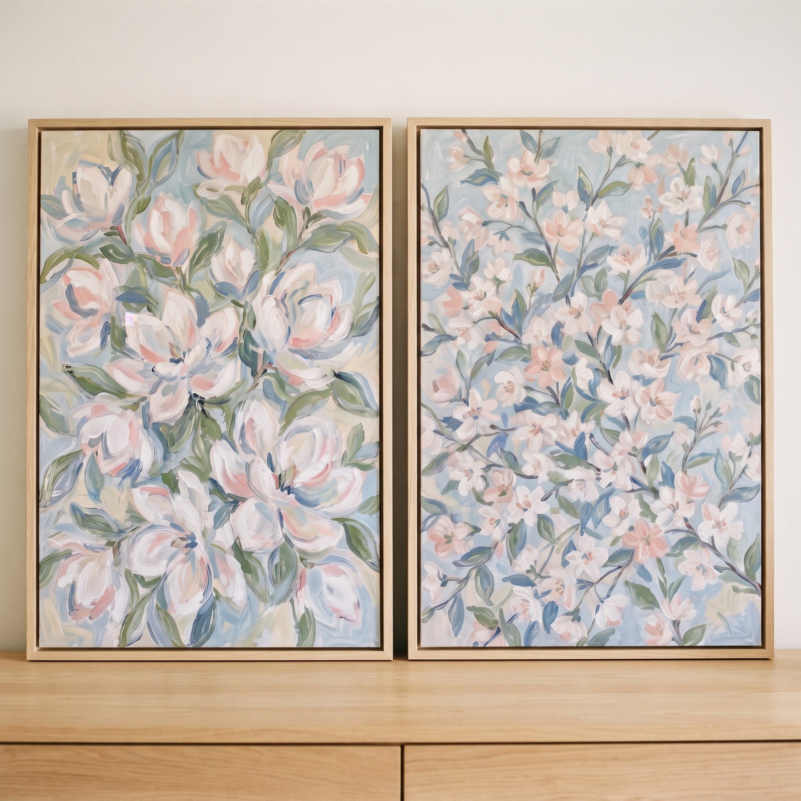 Soft pastel impressionist blossom floral wall art set of 2 framed and displayed on a light wood dresser.