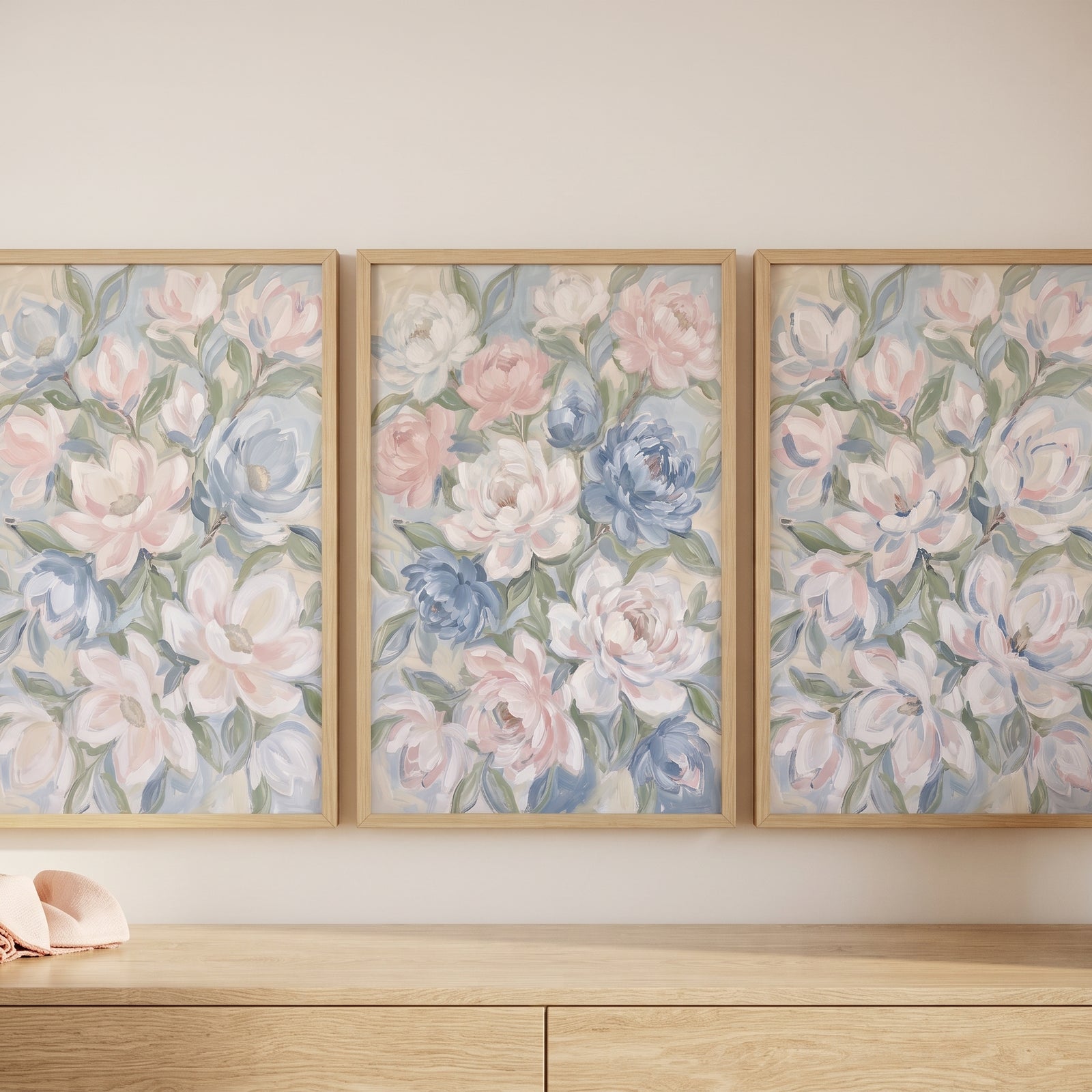 Soft pastel impressionist floral wall art set of 3 in light wood frames displayed on a wall above a matching dresser.
