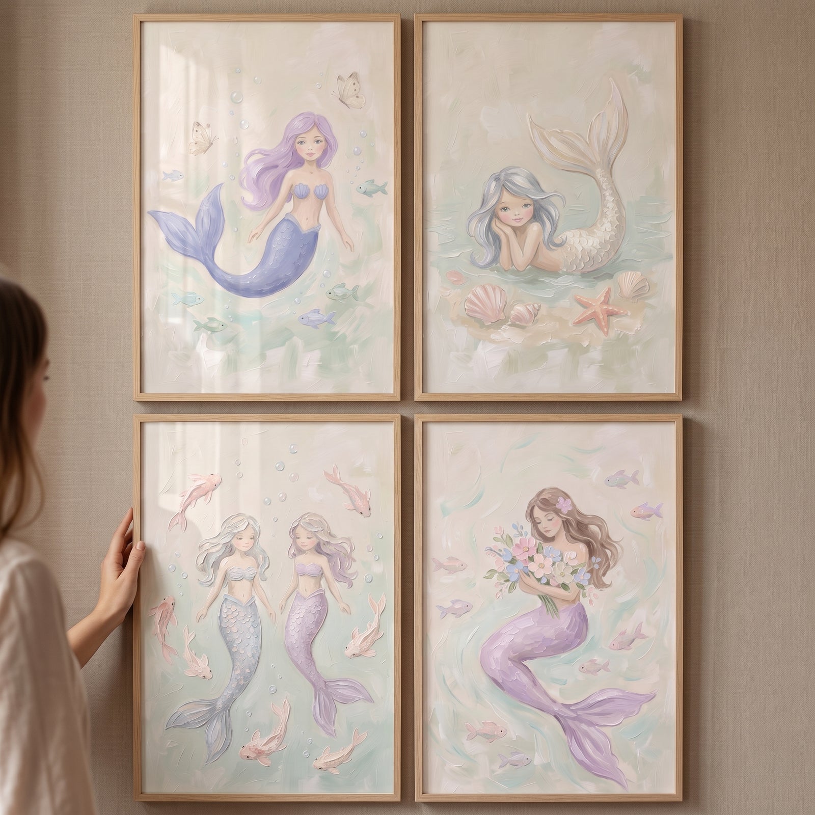Soft pastel ocean mermaid wall art set of 4 in wooden frames displayed on a wall as a person adjusts one frame.