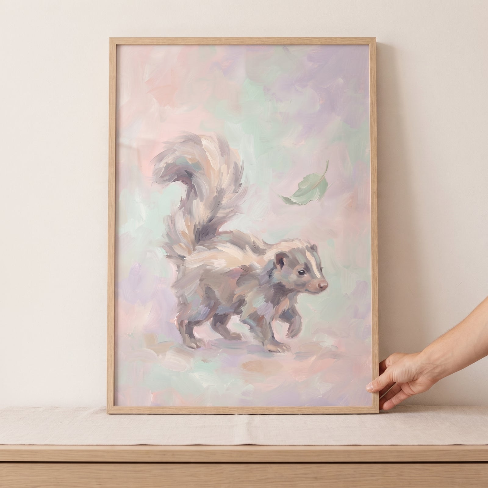 Framed soft pastel walking skunk wall art shows a striped animal and leaf against a background of soft color strokes.