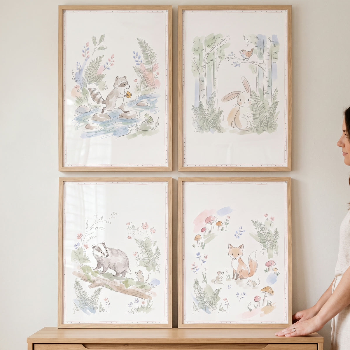 Soft pencil forest animals wall art set of 4 featuring a raccoon, rabbit, badger, and fox in light wood frames on a wall.