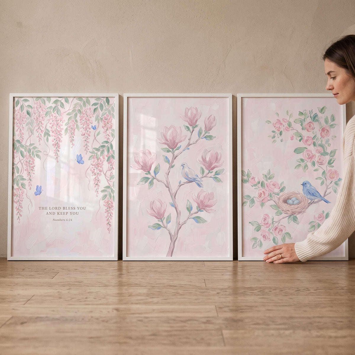 Soft pink blossom wall art set of 3 featuring birds, flowers, and a scripture verse leaning against a neutral wall.