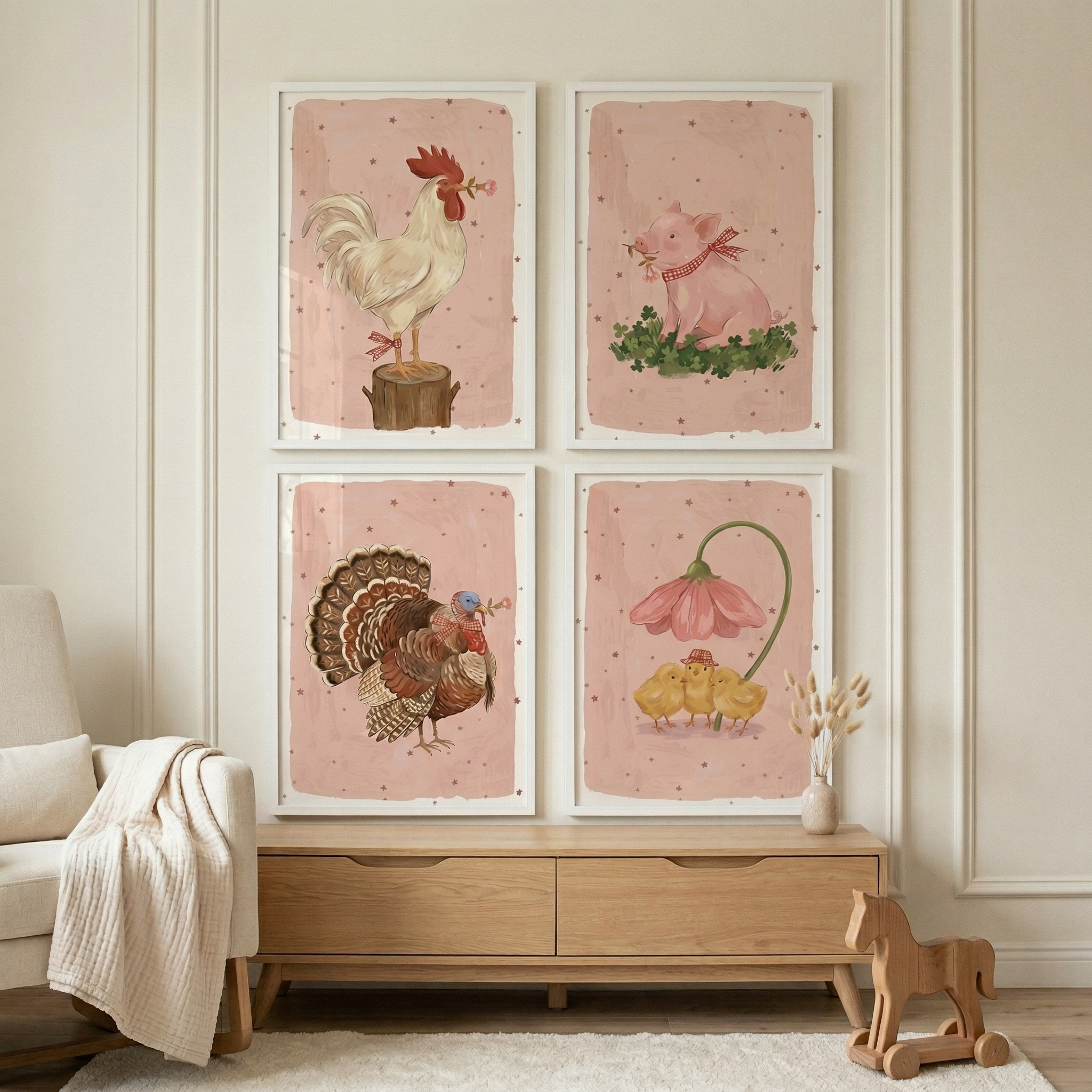 Four framed illustrations are arranged in a square grid on a light-colored wall above a wooden dresser. Each piece features a different farm animal against a soft pink backdrop with subtle dots. The top left shows a white rooster on a stump, while the top right depicts a pink pig with a red bow. The bottom left features a turkey with spread tail feathers, and the bottom right shows three yellow chicks sheltered by a large pink flower. A cream chair and a wooden toy horse add to the room.