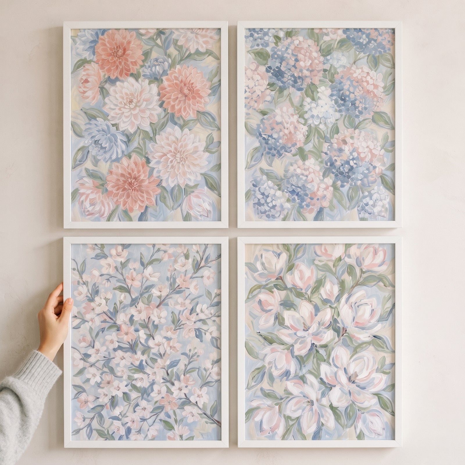 Hand touching a soft romantic garden floral wall art set of 4 featuring pastel flowers in simple white frames.
