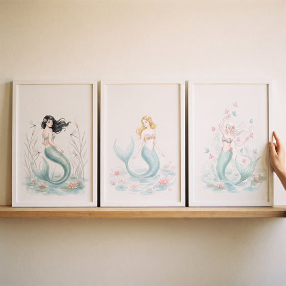 Soft teal tail mermaid wall art set of 3 framed watercolor illustrations on a wooden shelf.