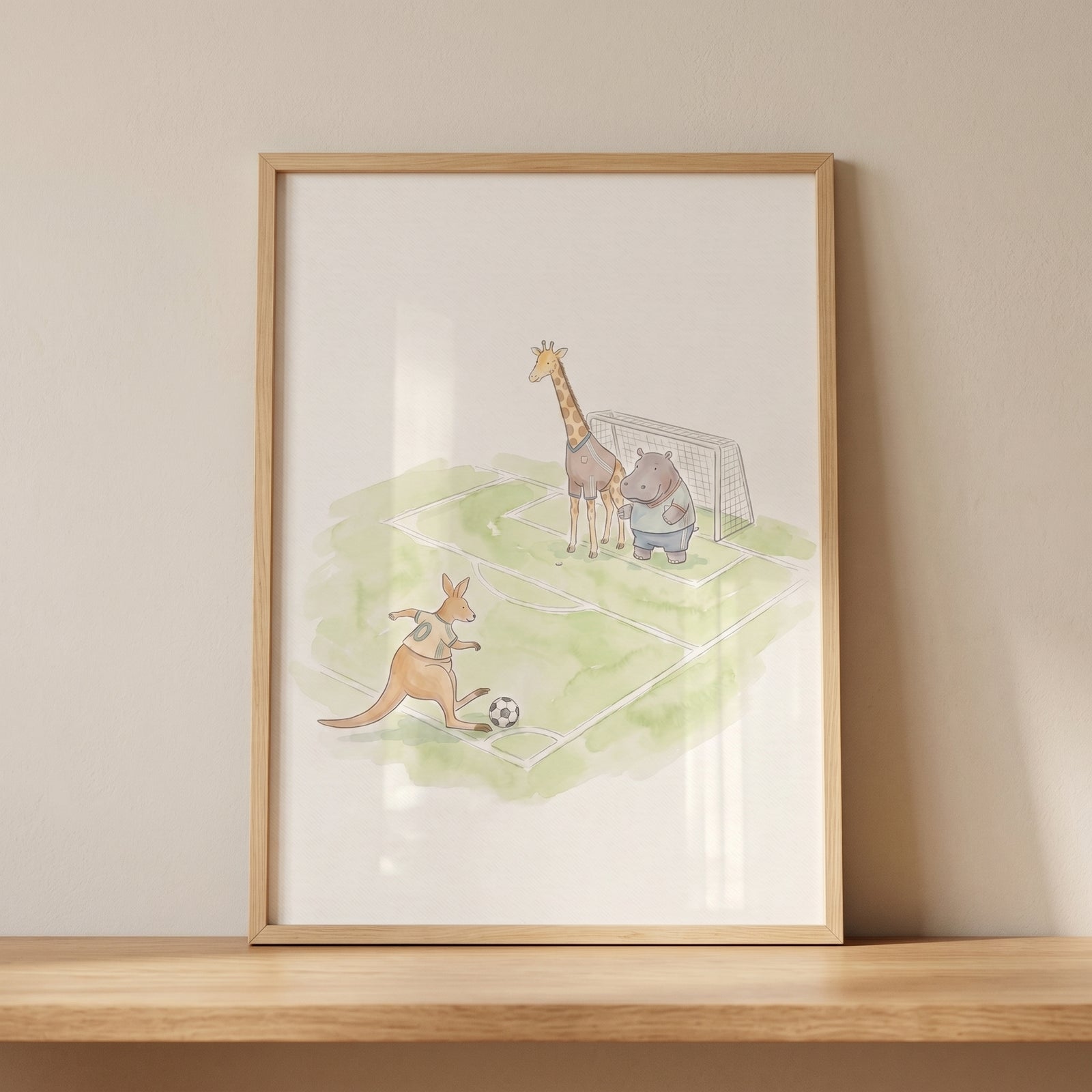 Framed soft watercolor animals wall art of a kangaroo, giraffe, and hippo playing soccer on a green field.