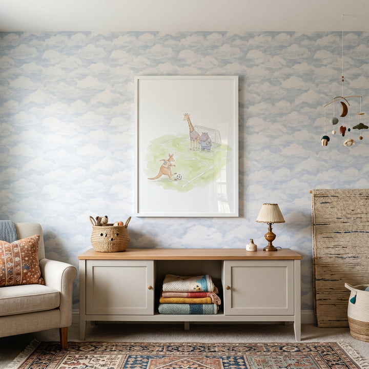 Soft watercolor animals wall art hangs above a grey console in a nursery with cloud wallpaper and a patterned rug.