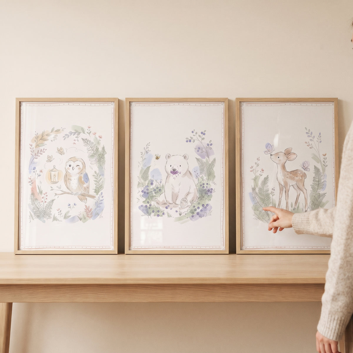 Soft watercolor woodland animals wall art set of 3 featuring an owl, bear, and deer in light wooden frames on a table.