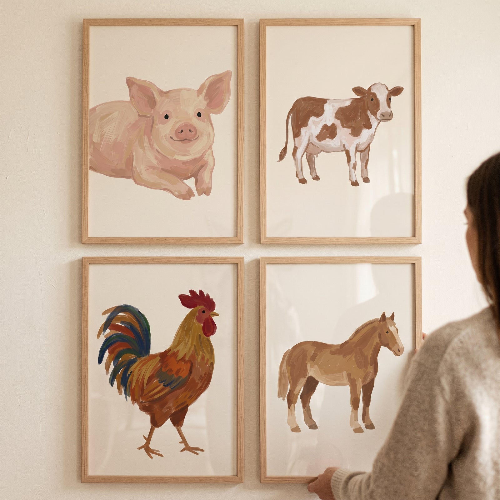 A person hangs a sophisticated earthy farm animals wall art set of 4 featuring a pig, cow, rooster, and horse in wood frames.