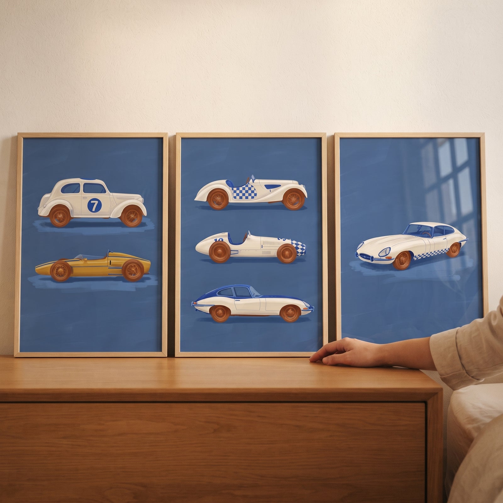 Sophisticated navy racing car wall art set of 3 in wood frames on a dresser featuring vintage car illustrations.
