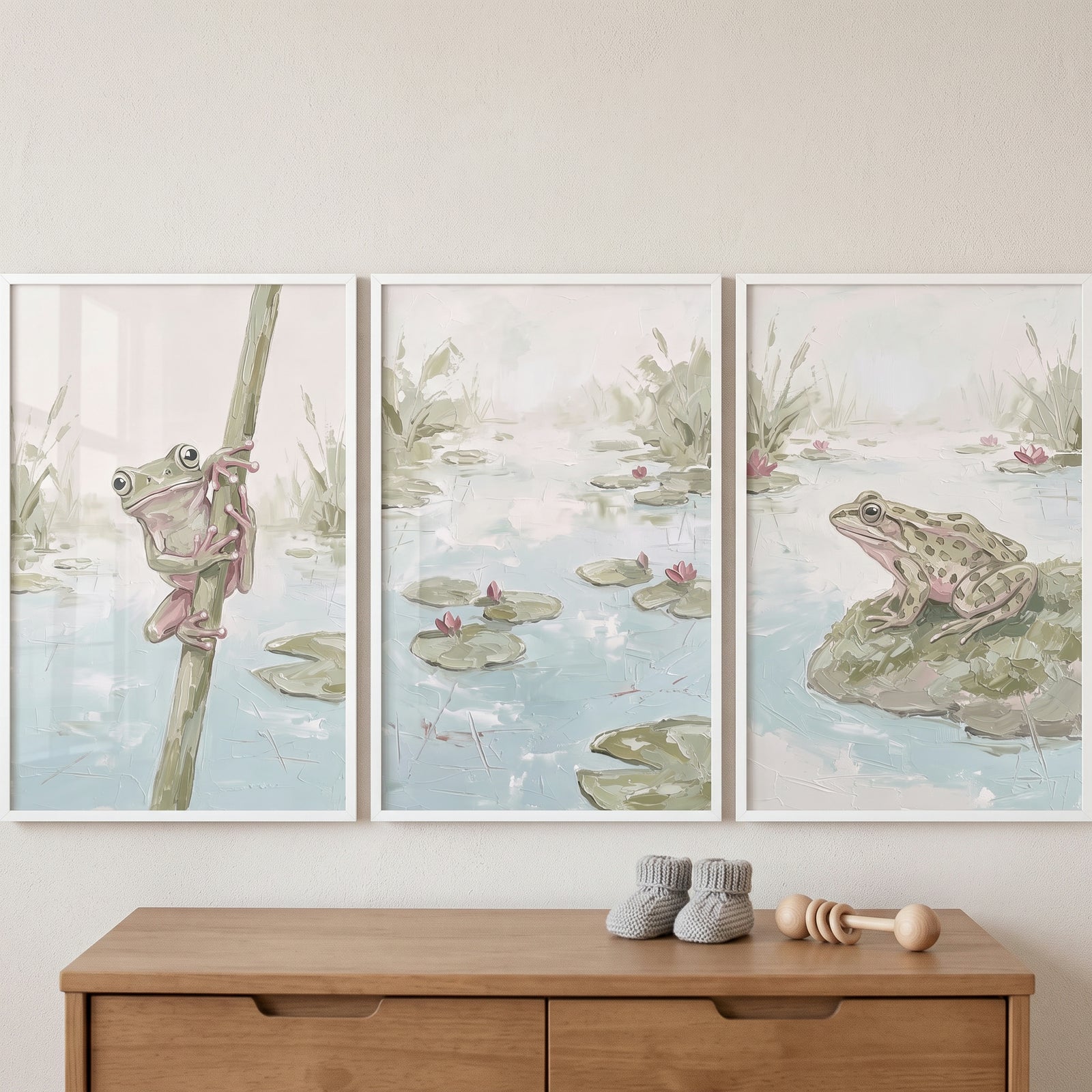 Sophisticated sage green frog wall art set of 3 hangs above a dresser with baby booties and a wooden rattle.