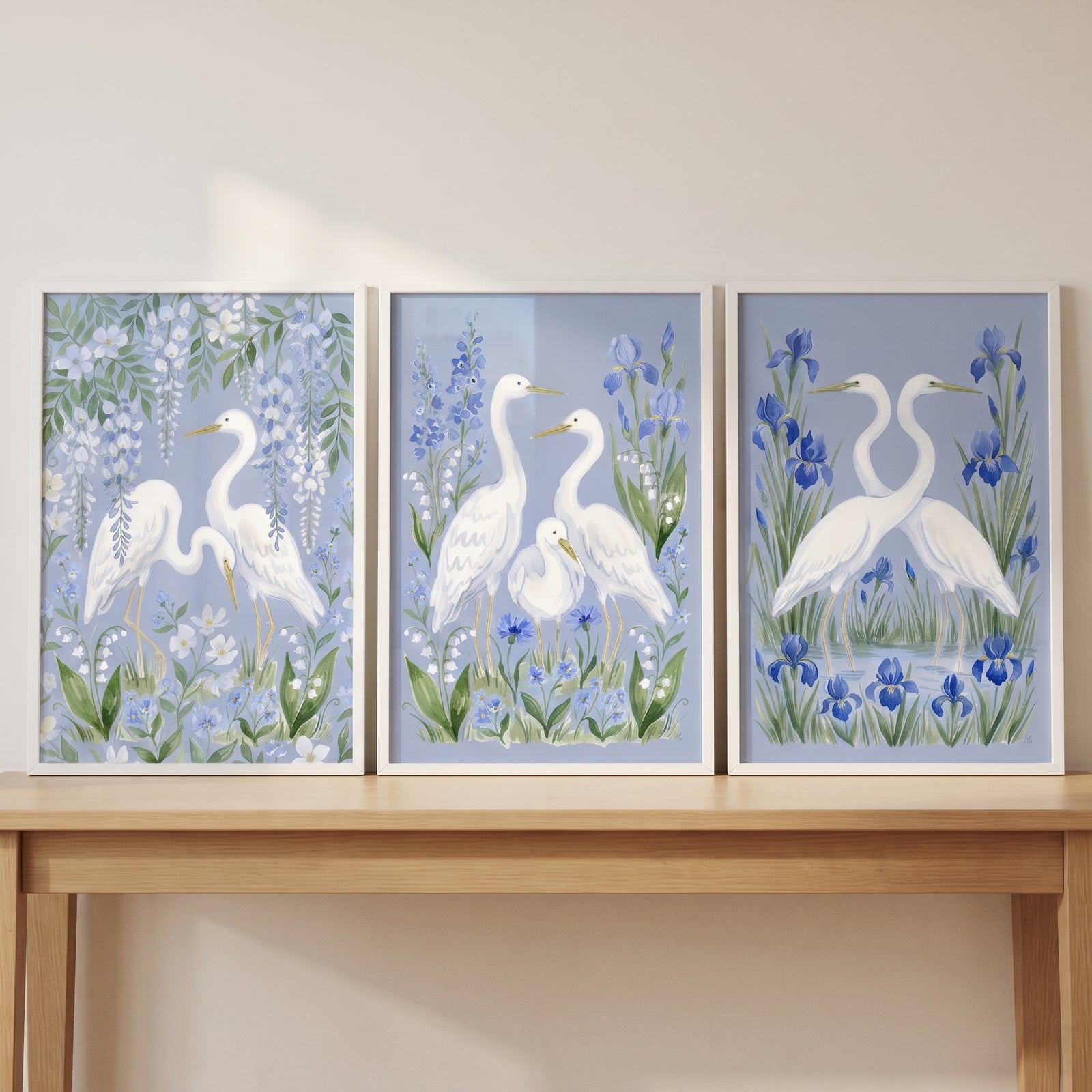 Southern charm botanical egret bird wall art set of 3 featuring white egrets and blue flowers on a light wood table.