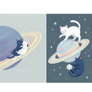 Two playful, space-themed illustrations featuring a white cat and a dark blue cat among colorful planets and stars. In the first image, the two cats cuddle together while floating along the pastel rainbow rings of a large planet. In the second image, the white cat stands on top of a rainbow-ringed planet while the dark blue cat floats nearby playing with a small moon, surrounded by scattered stars. 