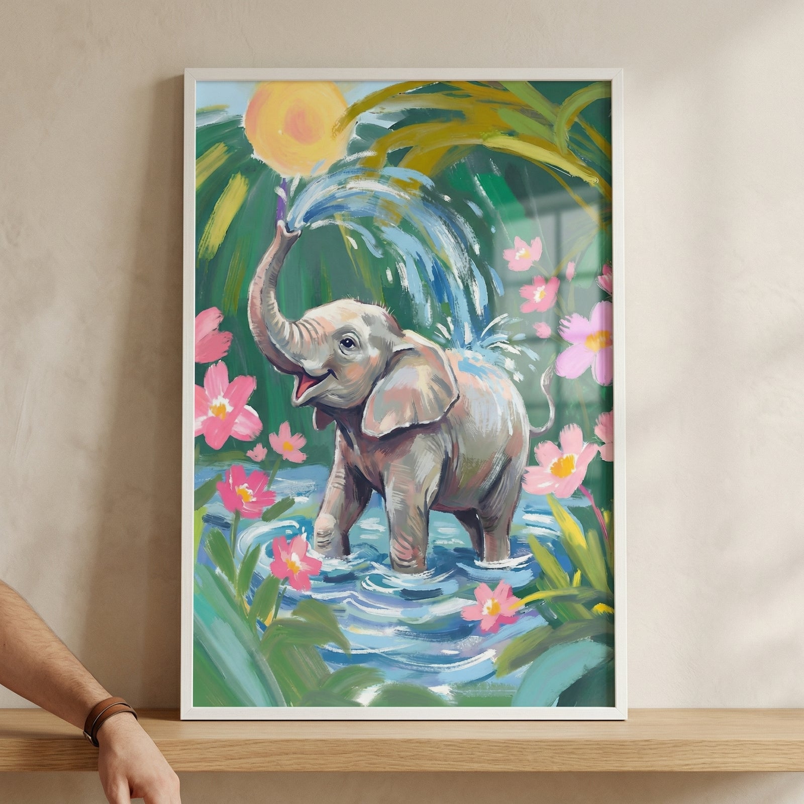 A framed, vibrant illustration features a cheerful young elephant standing in shallow blue water. The elephant has its trunk raised, spraying a fountain of water into the air. Around the elephant are bright pink flowers and lush green tropical foliage. A large, glowing yellow sun shines from behind the leaves. 