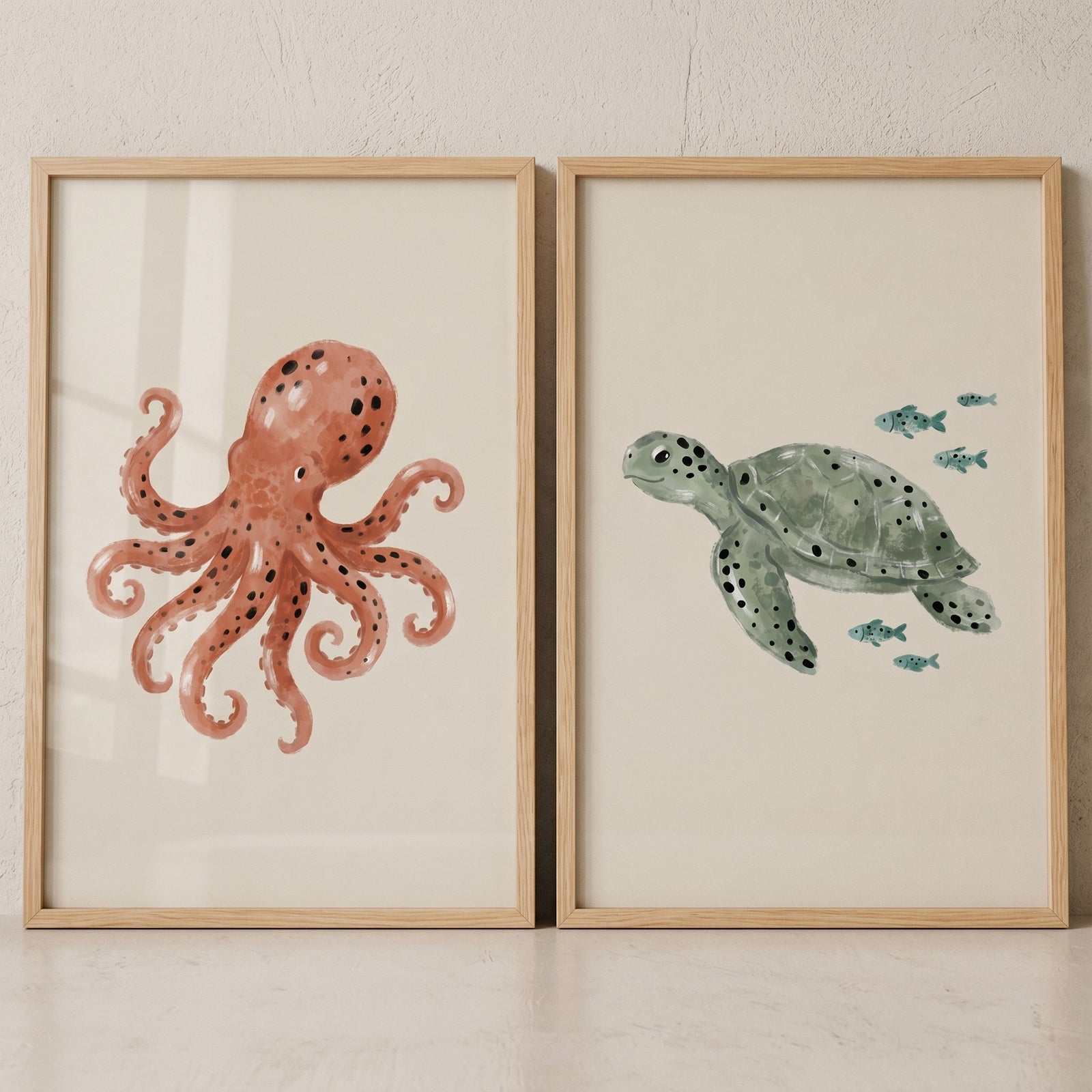 Spotted watercolor sea creatures wall art set of 2 featuring an orange octopus and a green sea turtle with small fish.