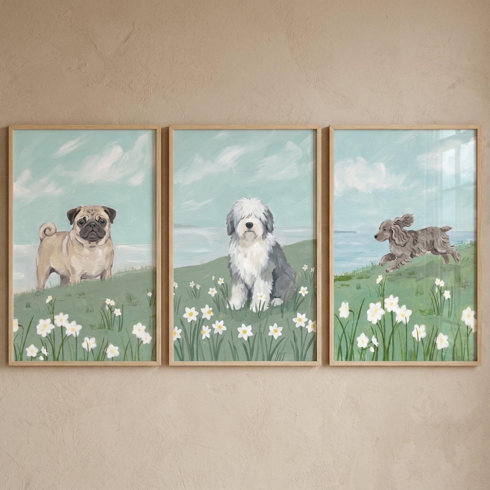 Pug, sheepdog, and running dog in a spring daffodil meadow dog wall art set of 3. Blue sky and light wood frames.
