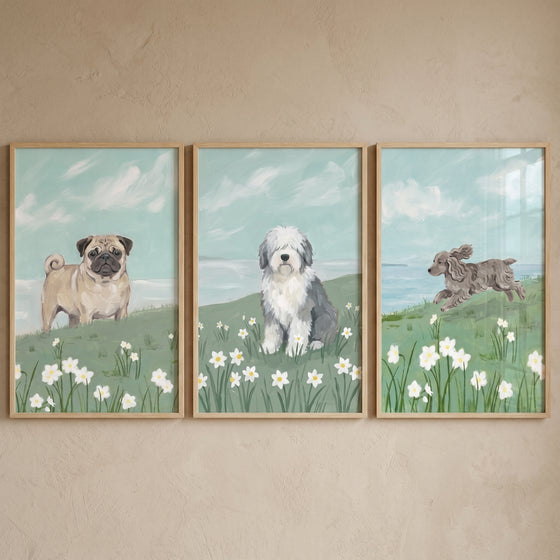 Pug, sheepdog, and running dog in a spring daffodil meadow dog wall art set of 3. Blue sky and light wood frames.