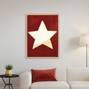 Modern living room with a white sofa, black side table, and floor lamp. A framed abstract painting of a large pale yellow star on a textured dark red background hangs above the sofa. A red pillow with embroidered stars rests on the sofa.