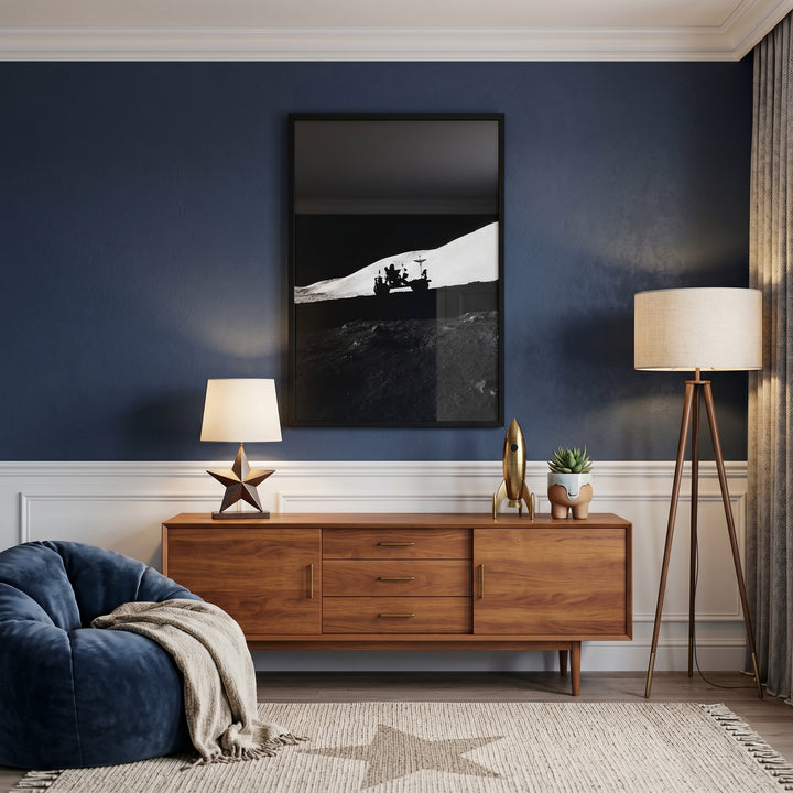 Mid-century room with stark silhouette lunar rover wall art above a wood sideboard. Tripod lamp and bean bag on a star rug.