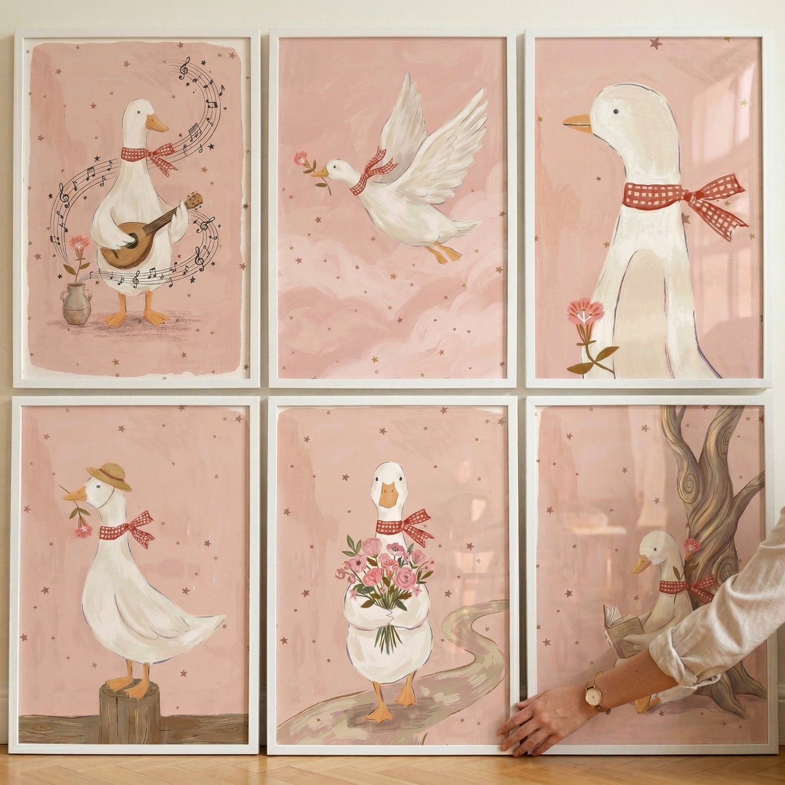 A collection of six whimsical illustrations presented in a two-by-three grid. The style is a gentle storybook folk art with soft, muted tones and a delicate, textured finish. Each illustration features a friendly white duck with a sweet expression, adorned with a red-and-white checkered ribbon tied in a bow around its neck. The background for each scene is a consistent dusty pink or blush color, sprinkled with faint, tiny scattered stars.
