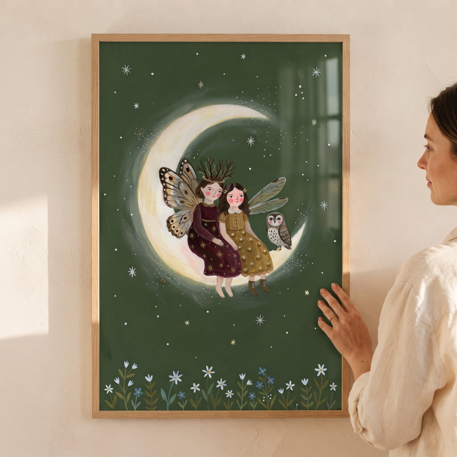 Two fairies and an owl sit on the moon in this starry crescent moon fairies wall art with a dark green floral background.