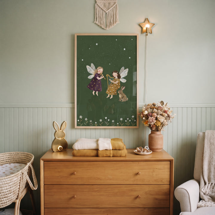 Starry green musical fairies wall art hangs above a wooden dresser in a sage green nursery with a wicker bassinet.