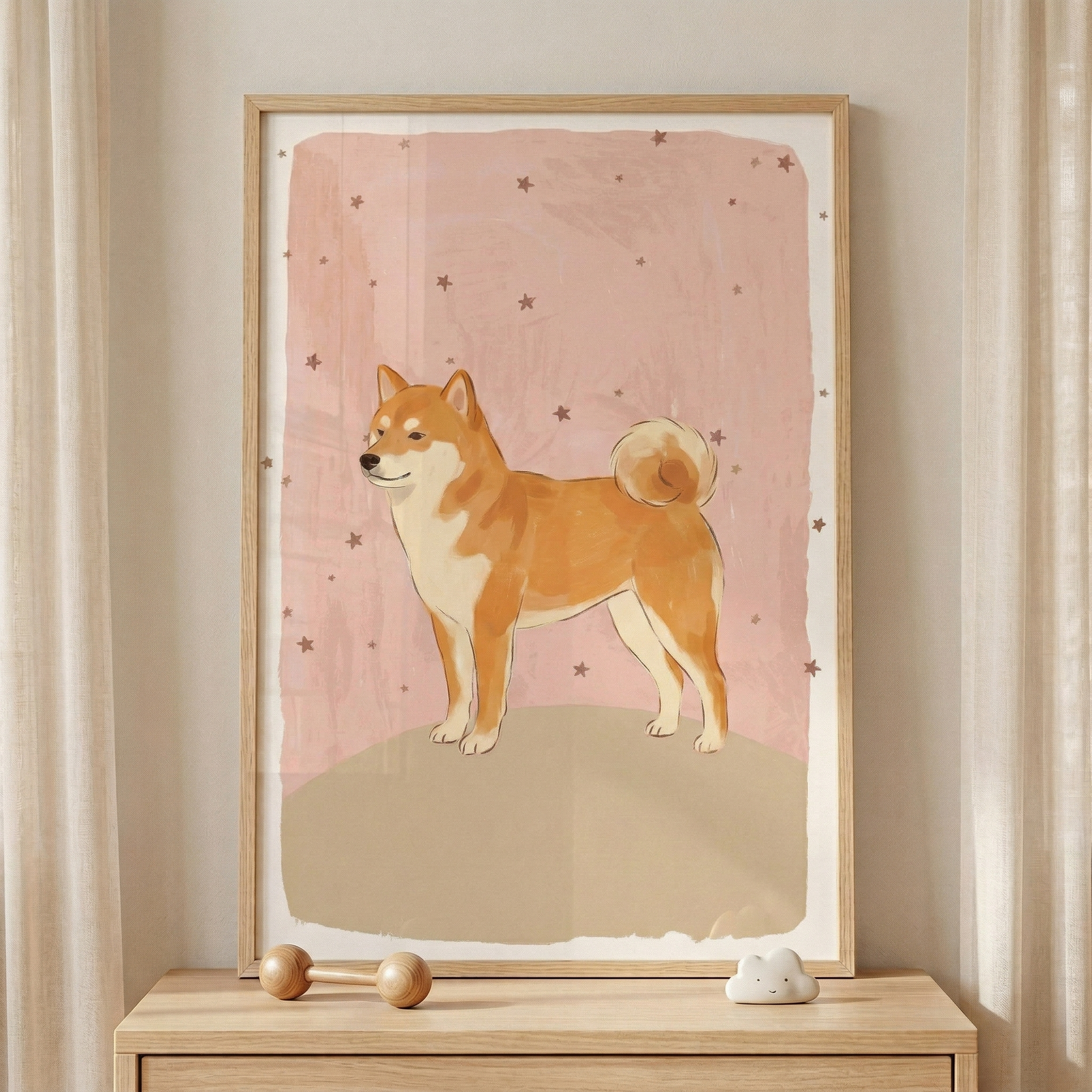 A framed illustration of a ginger-colored dog with white markings and a curled tail is displayed on a light wood dresser. The dog stands on a simple, rounded beige hill against a textured, pale pink background that is scattered with small, dark brown stars. The artwork is held within a natural wood frame. In front of the frame on the wooden surface, there is a small wooden toy shaped like a barbell and a tiny, white decorative object in the shape of a cloud. 