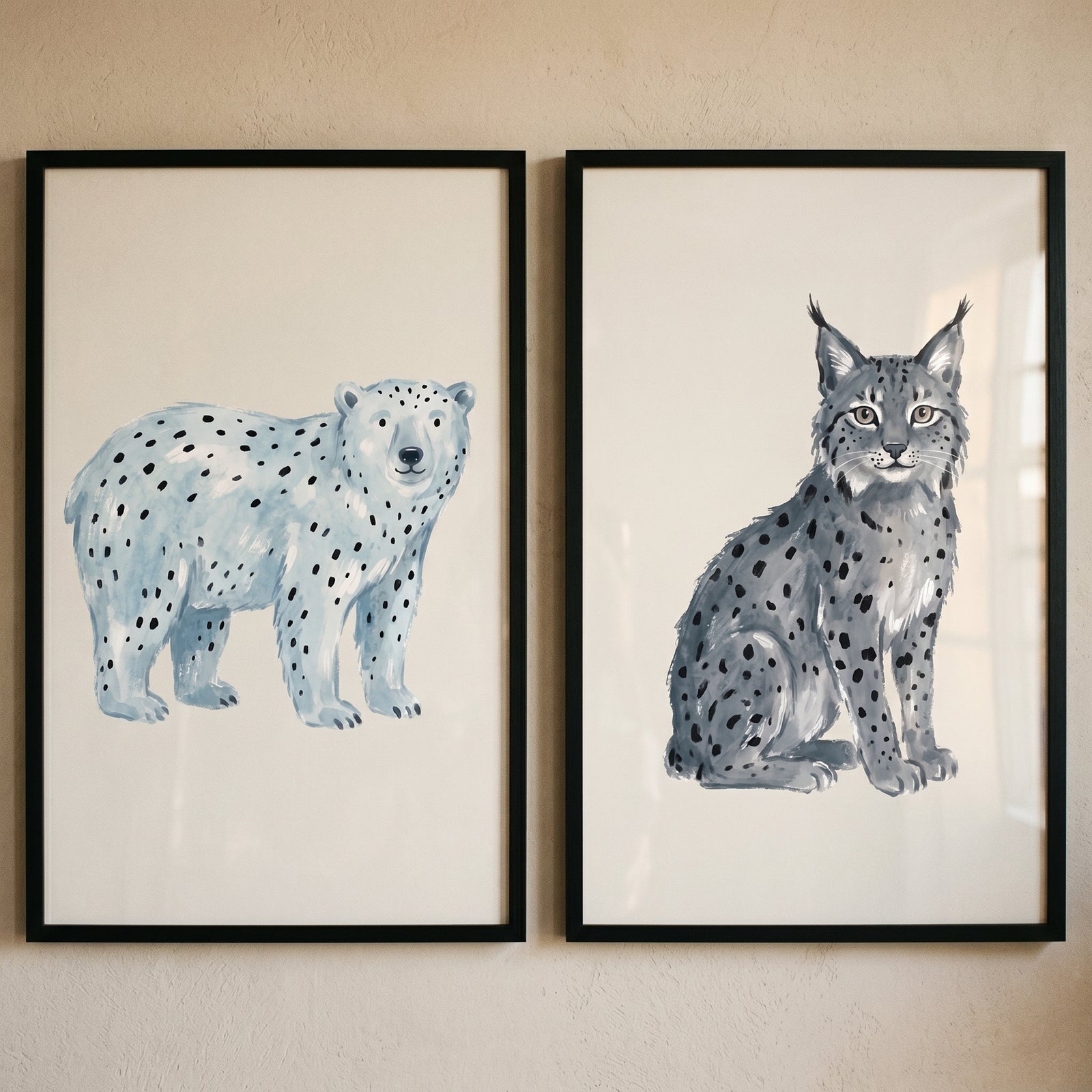 Stippled blue winter animals wall art set of 2 featuring a bear and a lynx in black frames on a neutral wall.