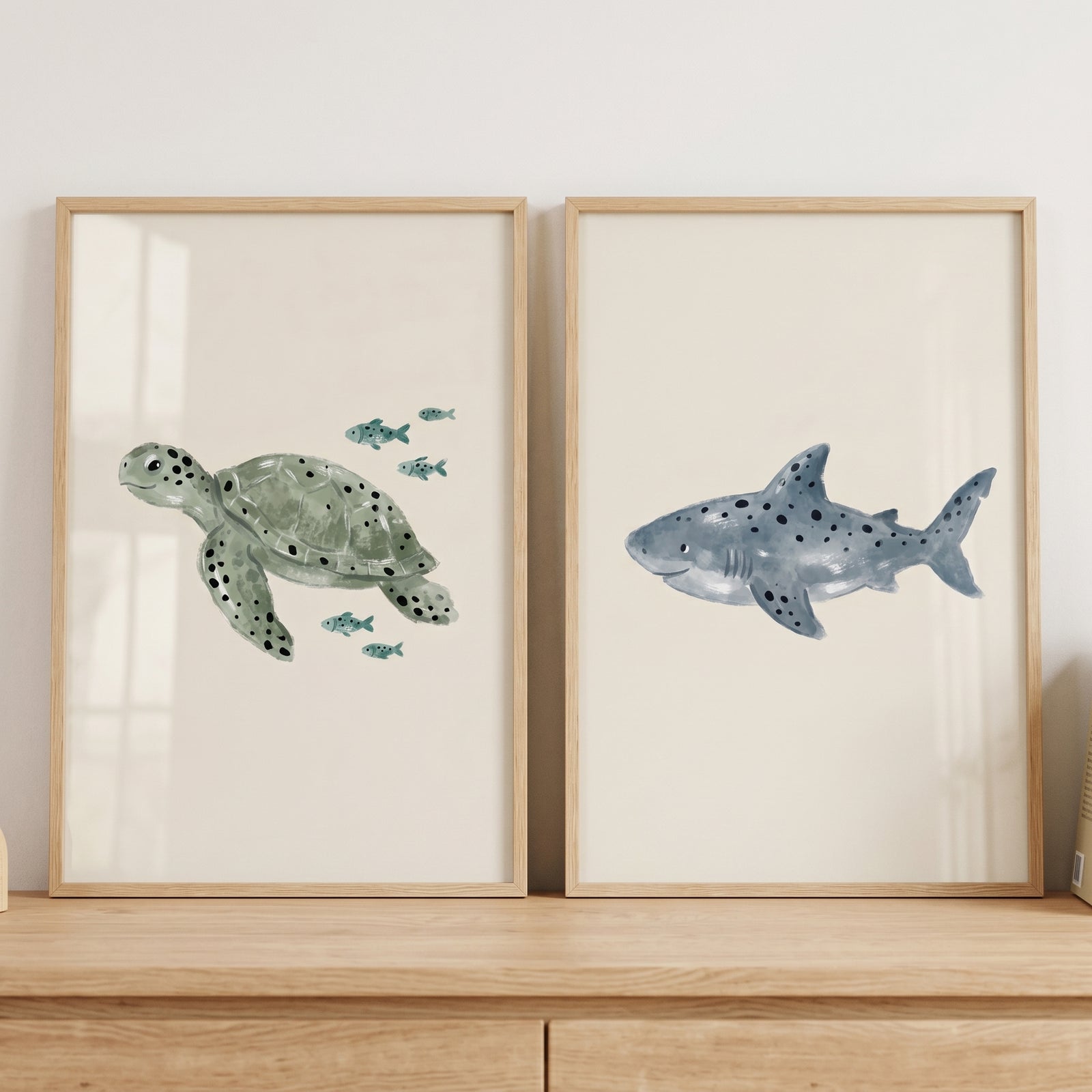 Stippled neutral sea animal wall art set of 2 with a green sea turtle and a blue shark in light wood frames.