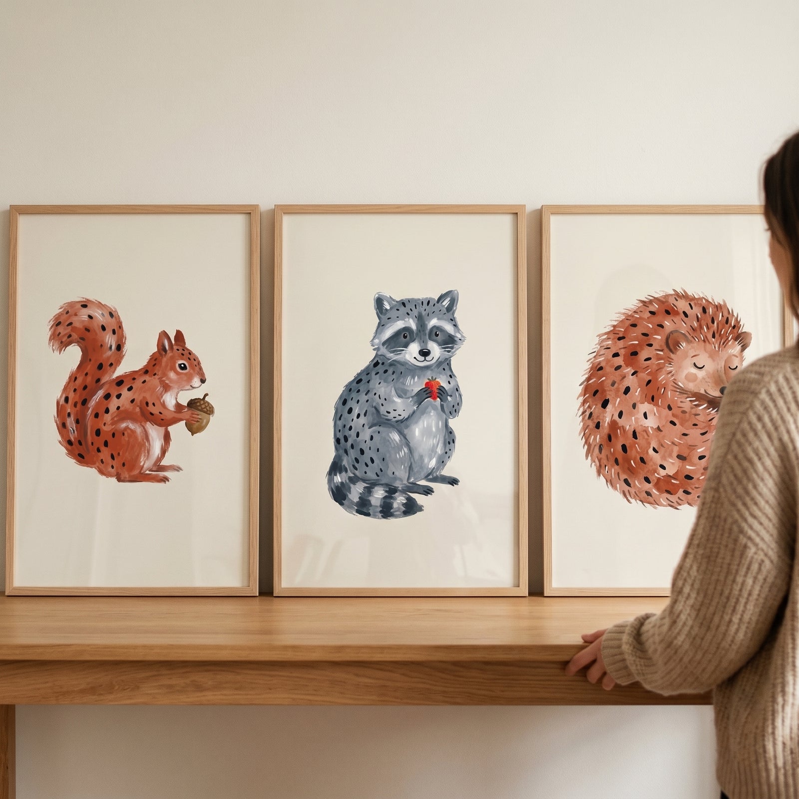 Stippled neutral woodland animals wall art set of 3 featuring a squirrel, raccoon, and hedgehog on a wooden table.