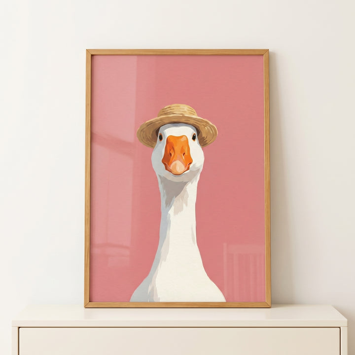 Framed straw hat white goose wall art with a pink background rests on a white dresser.