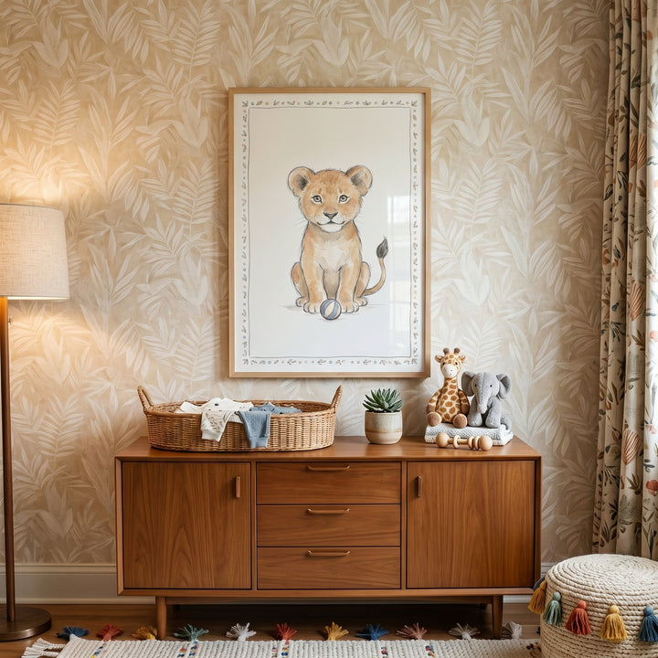 Striped ball lion cub wall art hangs above a wood dresser in a nursery with leaf-patterned wallpaper and plush toys.