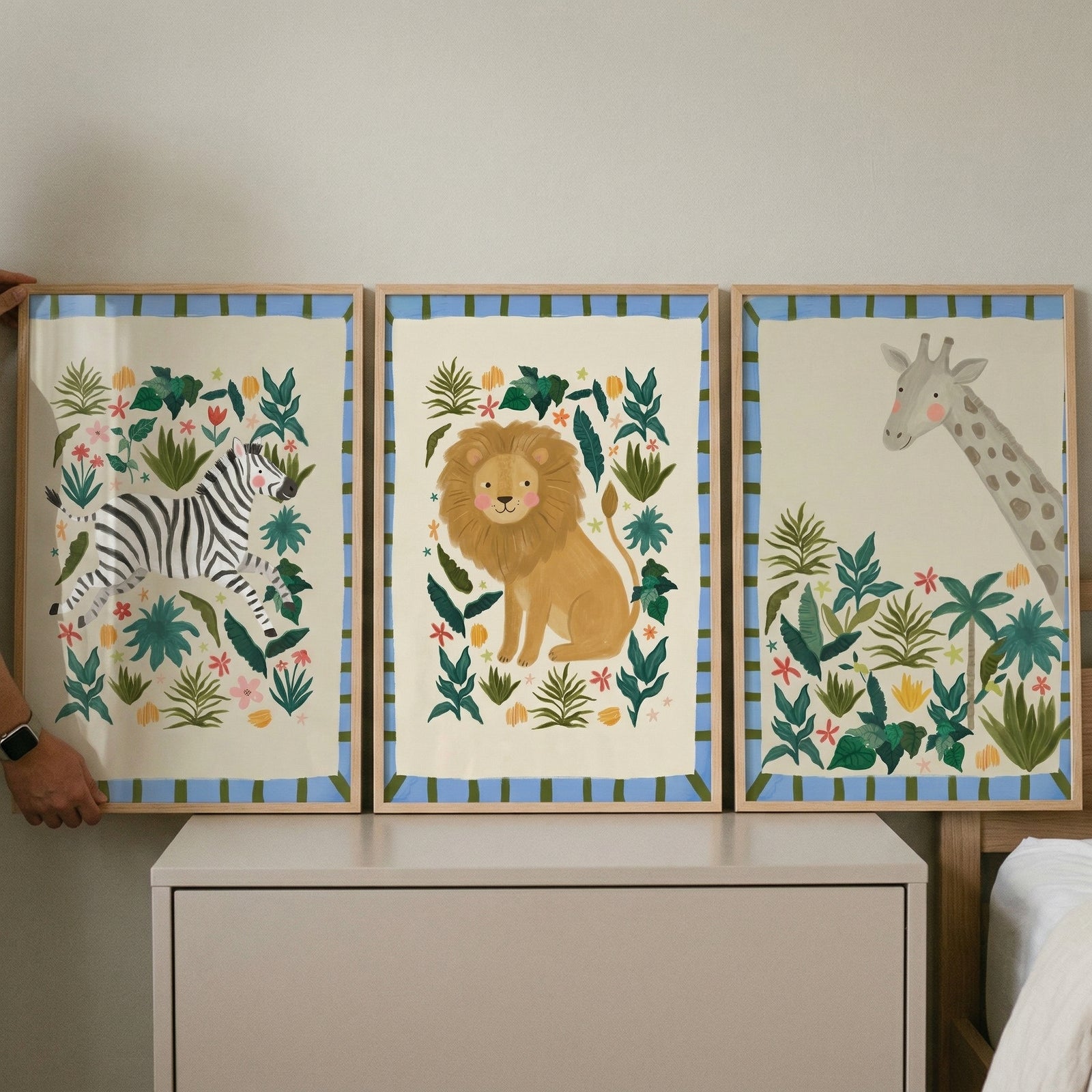 Striped border safari animal wall art set of 3 featuring a zebra, lion, and giraffe among green jungle leaves.