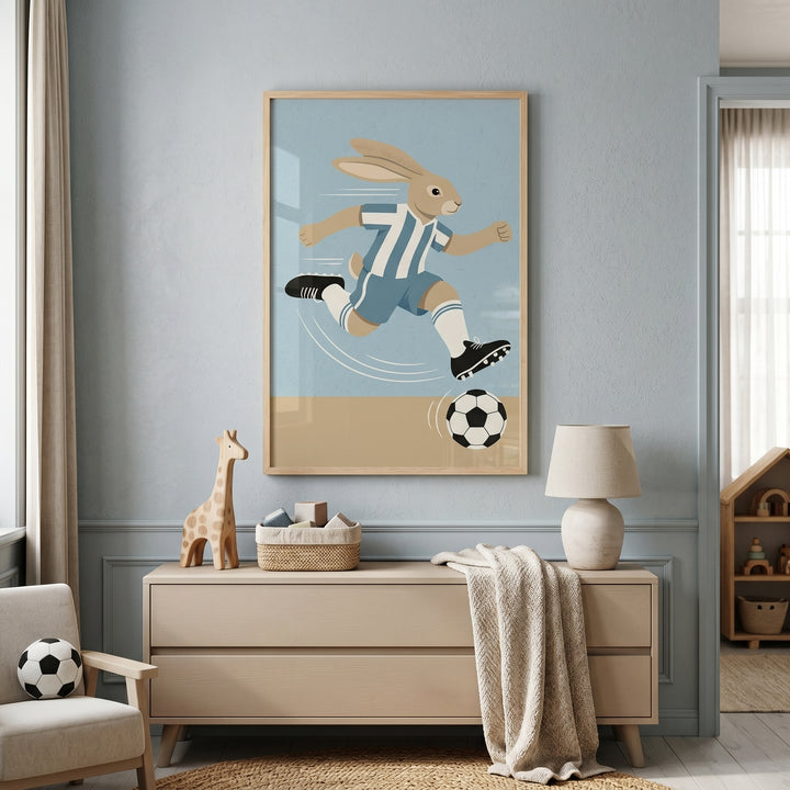 Striped jersey soccer rabbit wall art hangs above a dresser in a nursery with a giraffe toy and a soccer ball pillow.