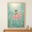 A framed vertical illustration hangs on a light wall above a wooden surface. The artwork shows a delicate female figure with translucent wings floating in a luminous teal environment, reaching toward a shimmering light from above. Her dress is made of soft petals in shades of peach and lavender. The scene includes gentle bubbles and aquatic plants. On the wooden surface below, a small, tan knitted teddy bear and wooden blocks sit next to the frame.