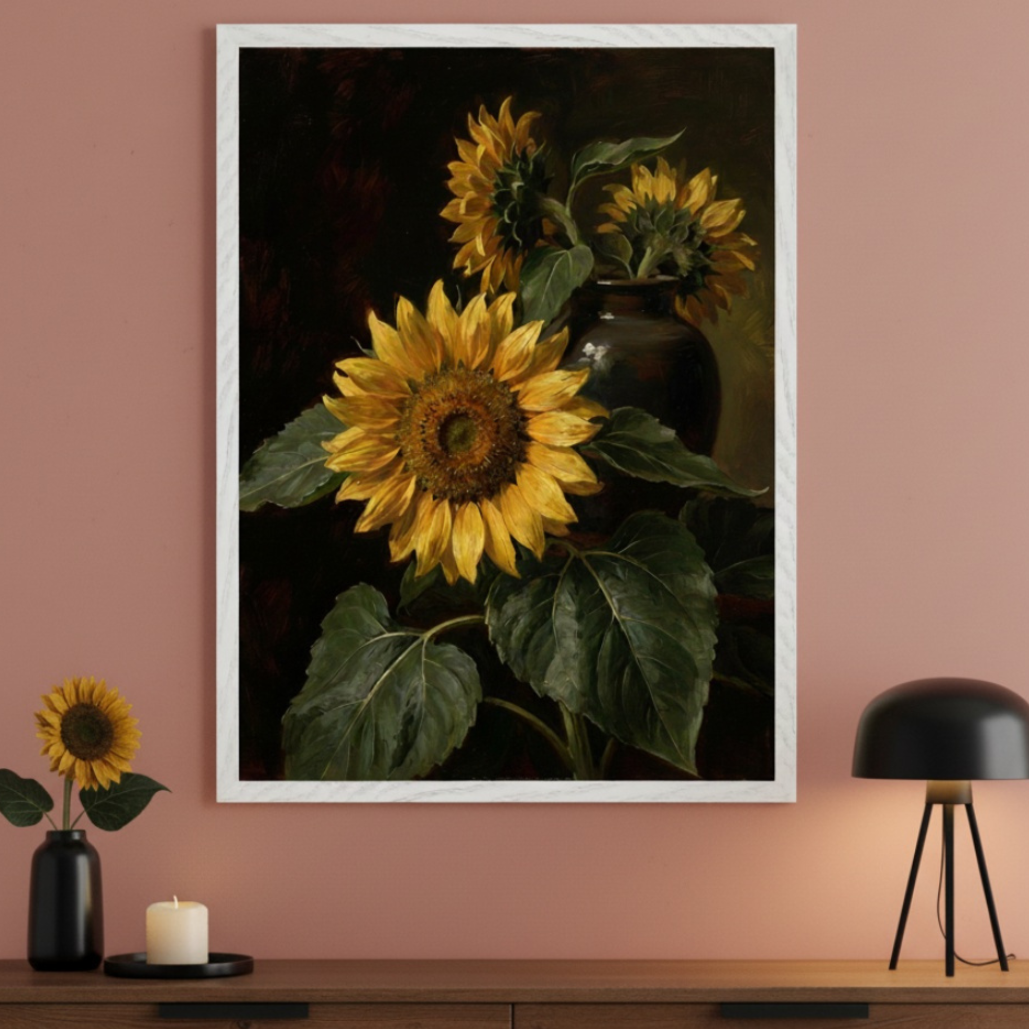 Modern room with a dark wood dresser. A large white-framed oil painting of sunflowers in a dark vase against a dark background hangs above the dresser. A small sunflower in a black vase, a lit candle, and a black table lamp are on the dresser.
