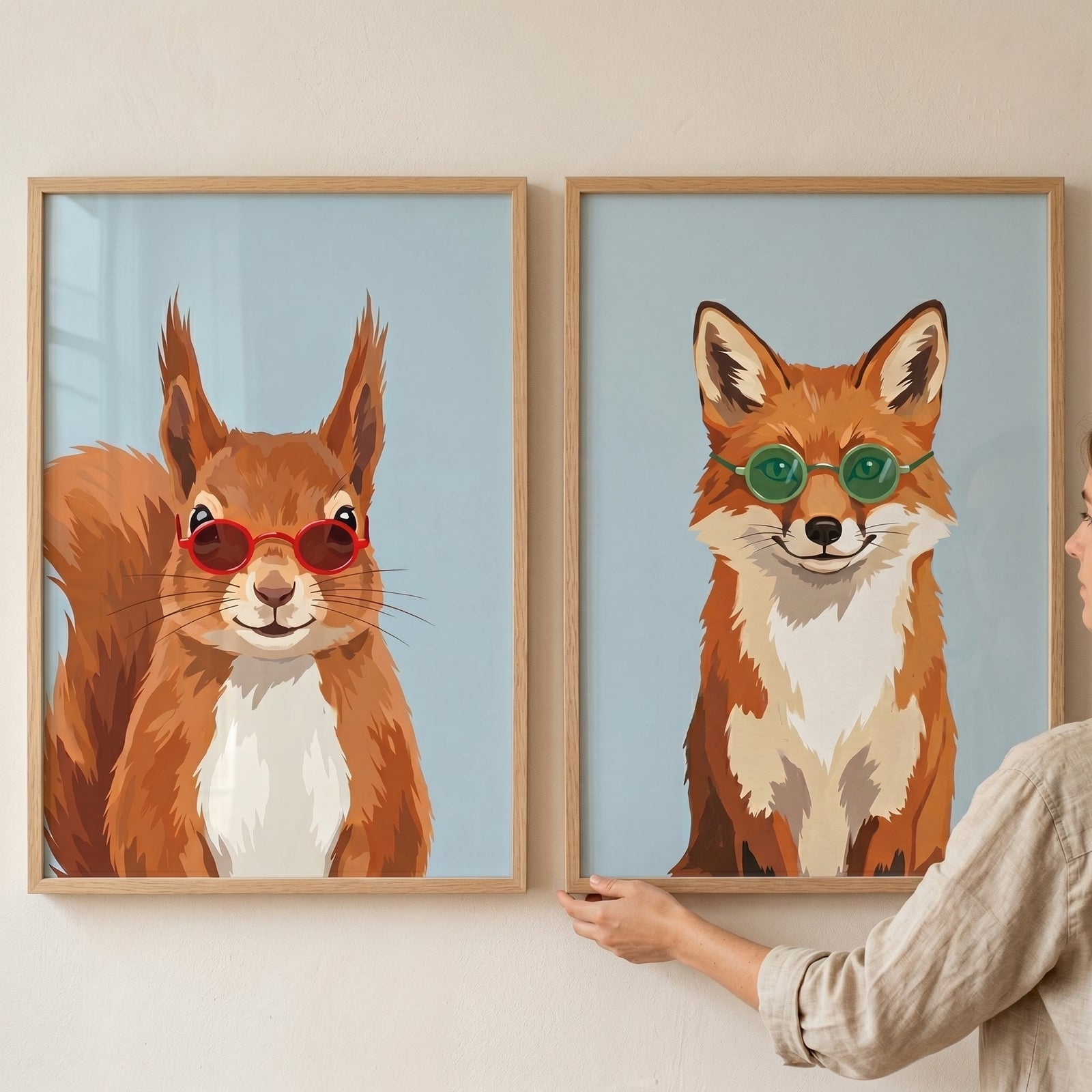 A person holds a sunglasses forest animal artwork set of 2 with a squirrel in red shades and a fox in green glasses.