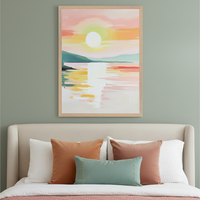 Bedroom with a beige upholstered bed and colorful throw pillows. A large framed impressionistic painting of a vibrant sunset over water and mountains hangs centered above the bed on a sage green wall.