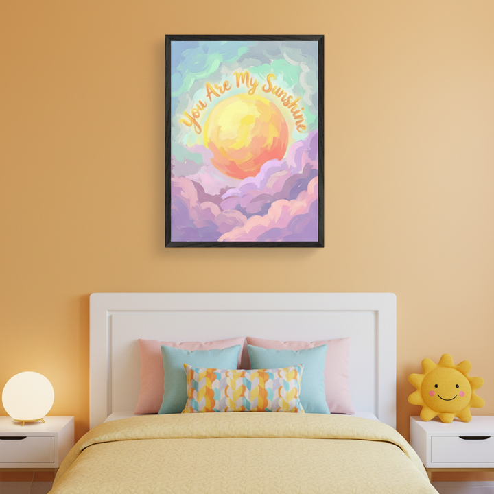 Kid's bedroom with a white bed and yellow quilt. A framed art print featuring a sun, purple clouds, and 'You Are My Sunshine' text in a painterly style hangs centered above the bed. White nightstands flank the bed, one with a lamp, the other with a sun plush toy.