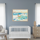 Modern nursery with a white crib and light gray armchair. A large framed painting depicts two children surfing on vibrant blue and green waves under a sunny sky, hanging above the crib. A light wood dresser with a surfboard and whale plush is on the right.