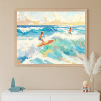 Two kids enjoy a day of surfing, one catching a wave on a red board while the other stands waist-deep in the ocean, surrounded by swirling blue and green waters. The framed artwork captures a warm sunset glow and hangs above a dresser with soft beach-themed accents.