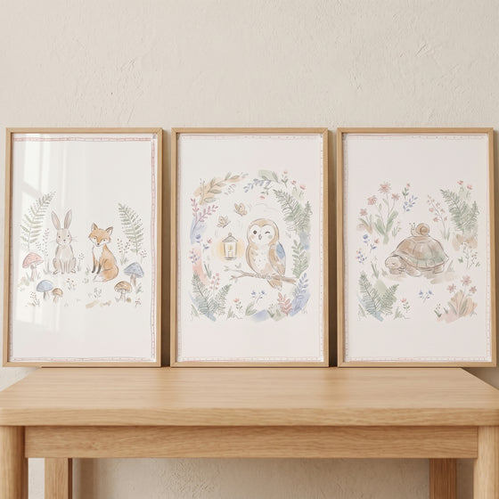Sweet pastel woodland animals wall art set of 3 featuring a fox, rabbit, owl, and turtle in watercolor on a wooden table.