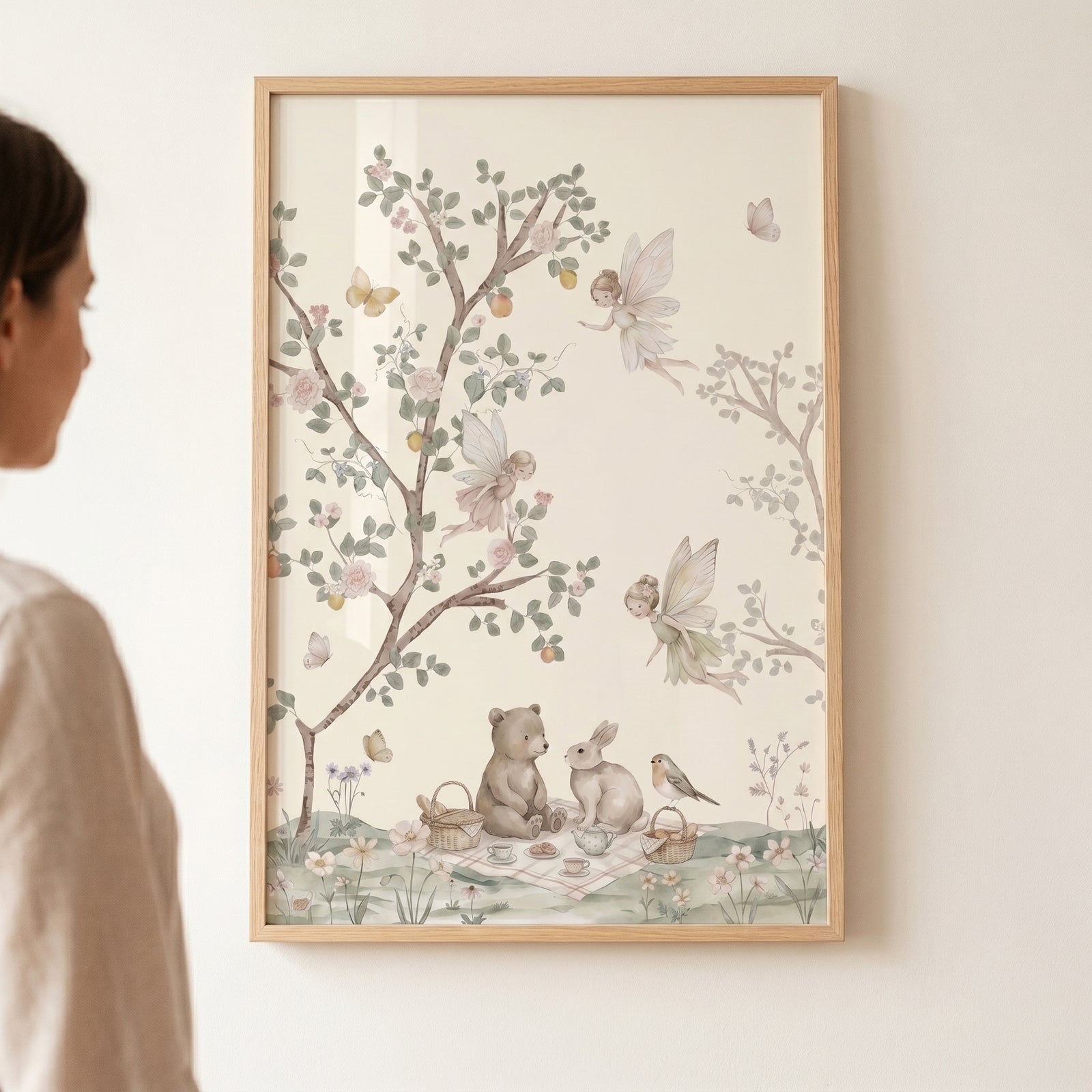 Tea party forest animals wall art shows fairies, a bear, and a bunny in a soft watercolor woodland scene in a wood frame.