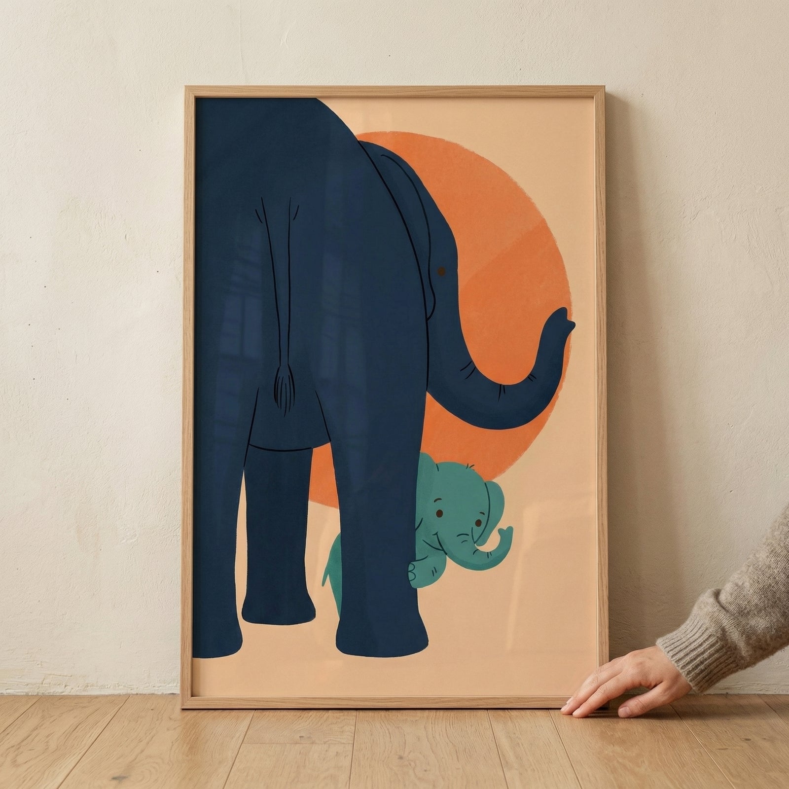 Framed illustration showing the back of a large blue elephant with a small green baby elephant peeking out from behind its legs in front of a warm orange circle. The playful composition creates a sense of protection and curiosity, making it a charming piece for a child’s room.