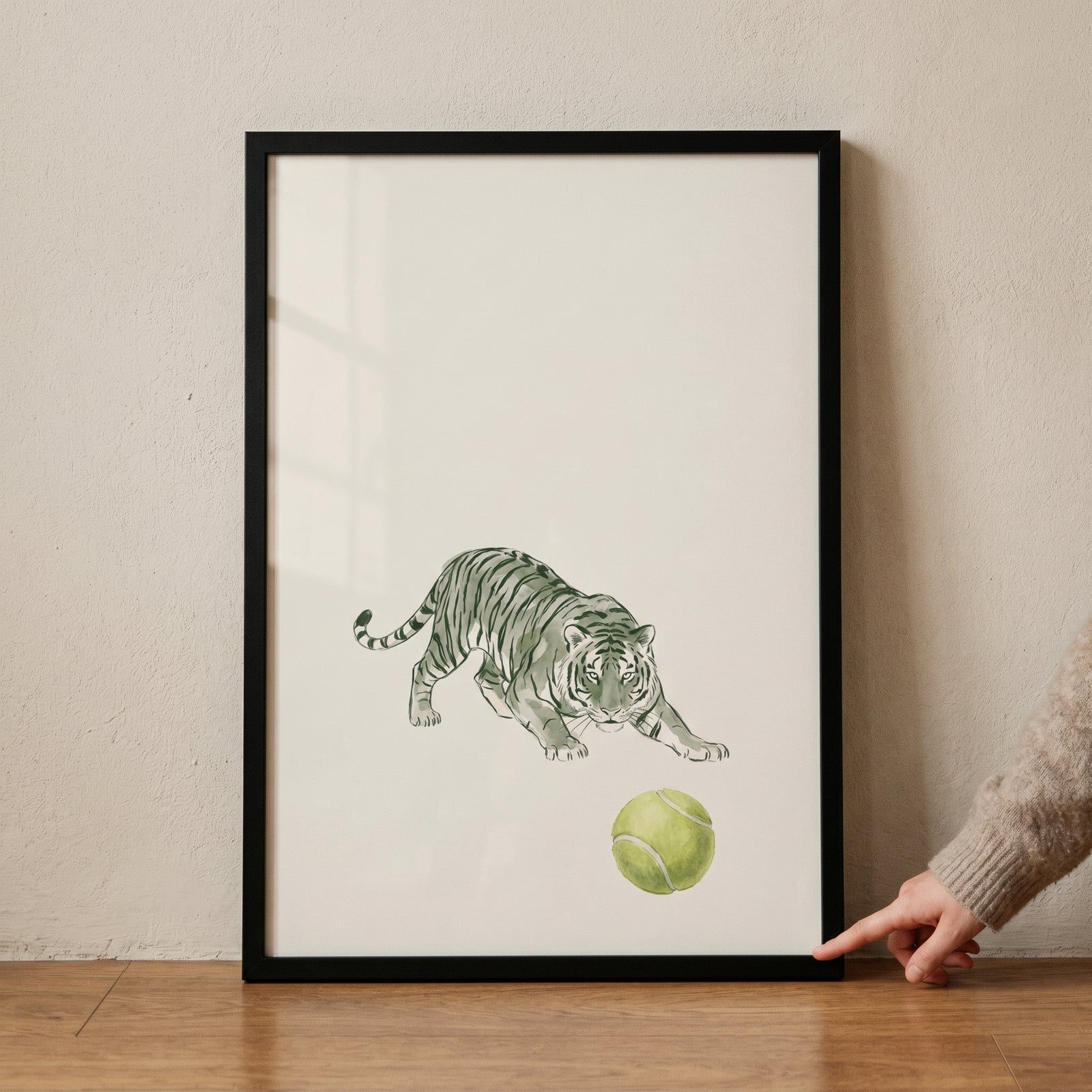 Framed tennis ball crouching tiger wall art features a green tiger stalking a ball on a plain white background.