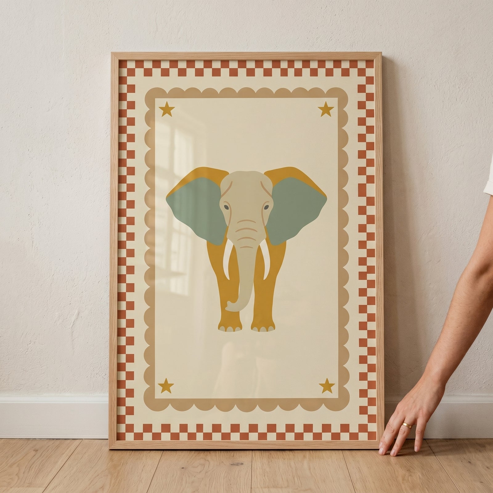 Terracotta checkered border elephant wall art with a yellow body, sage green ears, scalloped edges, and gold stars.